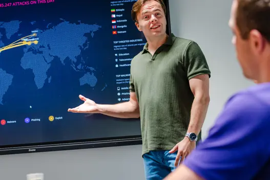 Security engineer presenteert bij scherm met informatie over cybersecurity-aanvallen