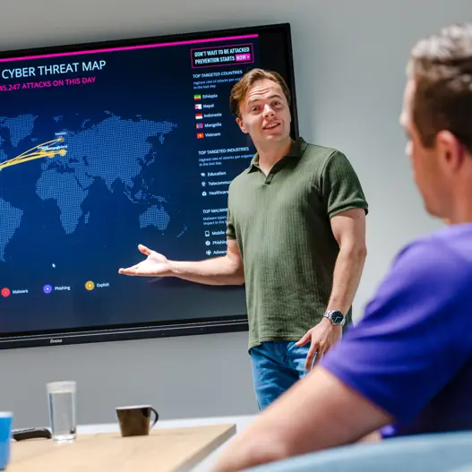 Drie security engineers in overleg aan tafel over cybersecurity, compliance en governance