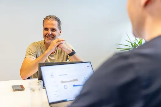 Collega’s van Harbers Group in gesprek aan vergadertafel met laptop