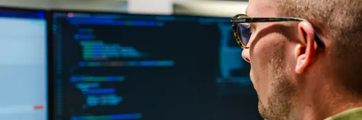 IT-expert van Harbers Group werkt achter computer met programmeercode op het scherm – illustratie van softwareontwikkeling, technische expertise en digitale innovatie.