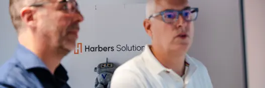 Twee IT-experts van Harbers Solutions zitten achter hun computer in overleg 