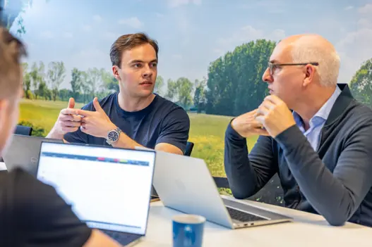 twee collega’s in bespreking aan tafel, gefocust in gesprek over een project of samenwerking.