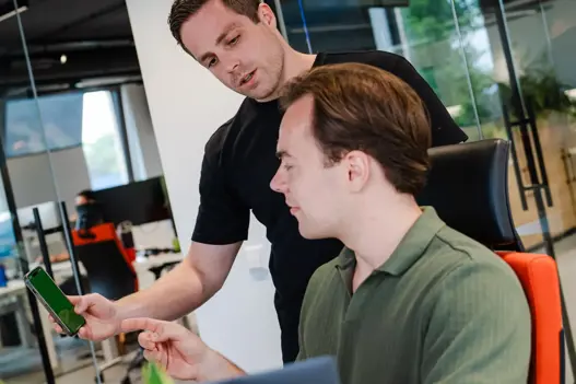 Twee security engineers overleggen achter computer over digitale dreigingen en beveiliging via telefoon