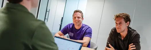 Drie security engineers in overleg aan tafel over cybersecurity, compliance en governance