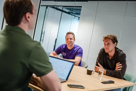 Drie security engineers in overleg aan tafel over cybersecurity, compliance en governance