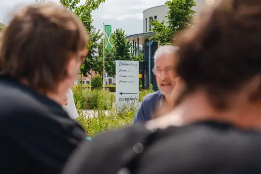 Bewegwijzeringsbord van Harbers Group met medewerkers buiten op de voorgrond
