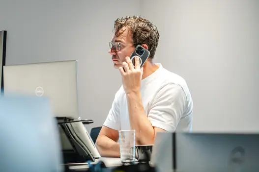 IT-expert belt met mobiele telefoon terwijl die achter computer werkt