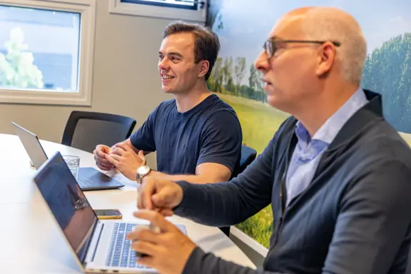 Twee collega’s in bespreking aan tafel, gefocust in gesprek over een project of samenwerking.