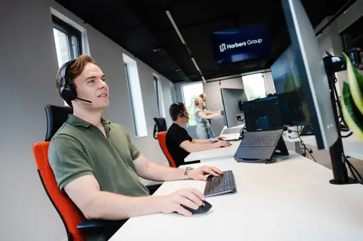 Supportmedewerkers van Harbers Group met headset achter laptop, actief in klantgesprekken