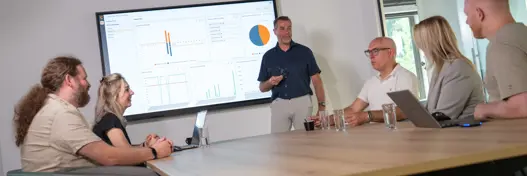 Overleg tussen IT-experts bij scherm met grafieken – representatie van strategisch advies en technische expertise.